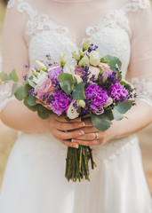 Closeup view of beautiful bridal bouquet in hands of young bride. Vertical color photography.