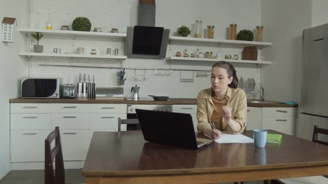 Mad husband coming into home kitchen to spouse networking on laptop, finding her obscene drawings. Fond of visual arts young wife being attacked by aggressive husband during creation of new picture.