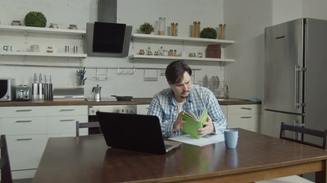 Anxious wife showing foreclosure notice to husband planning budget online on laptop while sitting in domestic kitchen. Man with horror reading eviction notice received due to non-payment of home loans