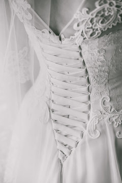 Vertical black and white color photography of elegant details of wedding dress. View from back.