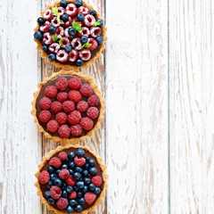 Raspberry and blueberry tartlets with chocolate ganache, fresh berries and mint leaves, selective...