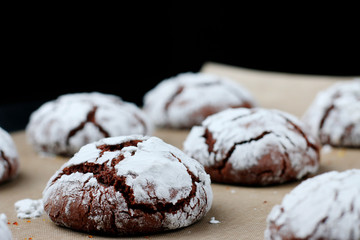 Chocolate cookies with cracks on baking paper and iolated on black. Cracked chocolate biscuits