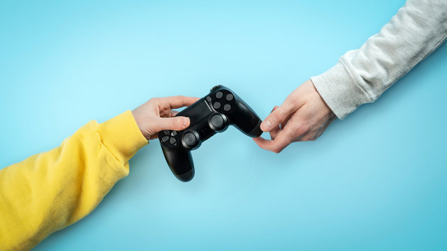 Black joystick in hands isolated on bright blue background