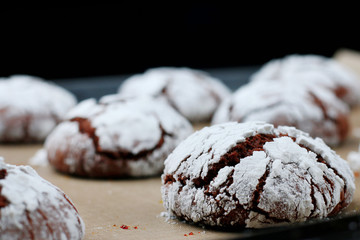 Chocolate cookies with cracks on baking paper and iolated on black. Cracked chocolate biscuits