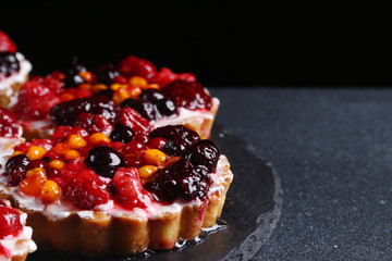 tart with berries on dark background. pie with raspberries and many berries