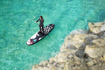 Woman Paddling on SUP board in a blue sea.
