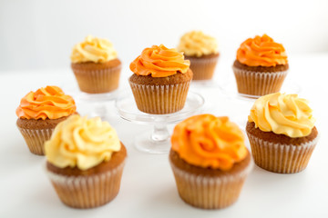 food, pastry and confectionery concept - cupcakes with buttercream frosting over white background