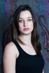 Vertical closeup of gorgeous brunette young woman in black tank top in front of multicoloured background