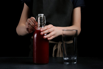 girl pouring juice in glass on dark background. summer drink concept