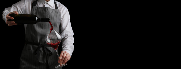 the waiter pours wine in glass baner on dark background