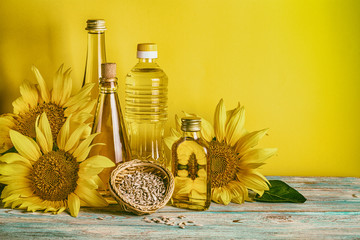 Rural still-life - sunflower oil in bottles with flowers of sunflower (Helianthus annuus), closeup