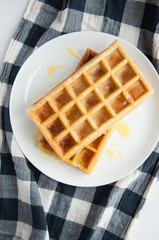 Belgian waffles on a white plate on the table. French or American breakfast. Vintage style. Sweet food.