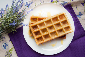 Belgian waffles on a white plate on the table. French or American breakfast. Vintage style. Sweet food.