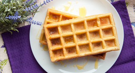 Belgian waffles on a white plate on the table. French or American breakfast. Vintage style. Sweet food.