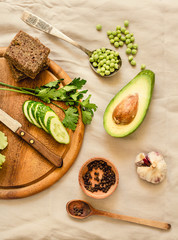 Ingredients for guacamole on a wooden board. Parsley, avocado, garlic, black pepper. Top view.