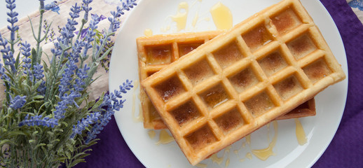 Belgian waffles on a white plate on the table. French or American breakfast. Vintage style. Sweet food.