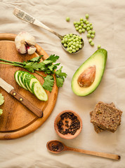 Ingredients for guacamole on a wooden board. Parsley, avocado, garlic, black pepper. Top view. Diet detox food concept.