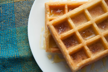 Belgian waffles on a white plate on the table. French or American breakfast. Vintage style. Sweet...