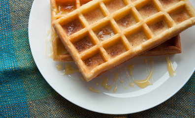 Belgian waffles on a white plate on the table. French or American breakfast. Vintage style. Sweet...