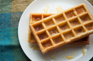 Belgian waffles on a white plate on the table. French or American breakfast. Vintage style. Sweet food.