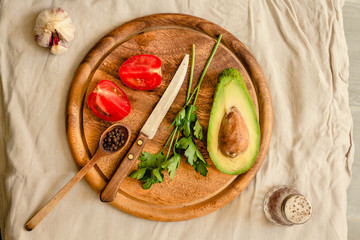 Ingredients for guacamole on a wooden board. Parsley, avocado, tomatoes, garlic, black pepper.Top view.
