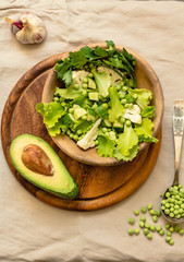Fresh delicious green salad with avocado in a wooden plate and gluten free toast. Top view. Healthy lunch dish and Diet detox food concept.