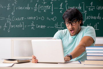 Young male student mathematician in front of chalkboard
