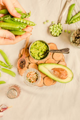 Avocado sauce (guacamole) with sweet green peas and rosemary in a metal dish. Top view.. Hands of a young woman