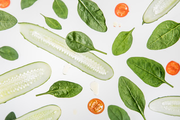 background with sliced red tomatoes, spinach leaves and cucumbers on grey