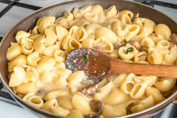 Pasta carbonara with mushrooms is cooked in a pan - Italian cuisine