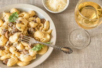 Homemade pasta carbonara with mushroom cream sauce on a plate close-up and a glass of dry white wine - Italian cuisine, lunch.