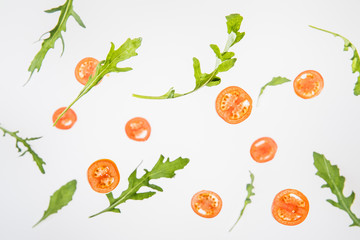 sliced red tomatoes and  green arugula leaves on grey background