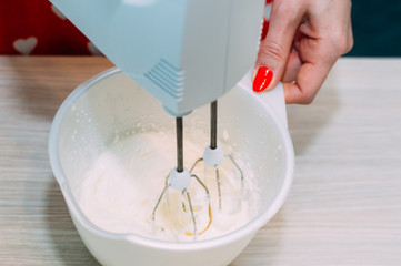 woman whips a sponge cake with a mixer. Close-up