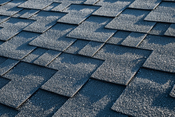 Close up view on asphalt roofing shingles covered with frost