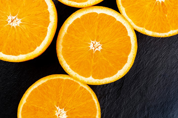 A closeup photo of vibrant orange halves, shot from above on a black background with copyspace