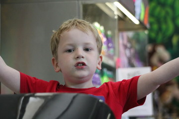 little boy in red top with arms up