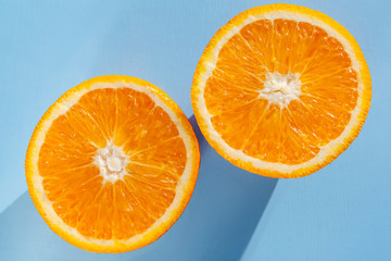 two slices of bright juicy orange on a blue background, flat lay