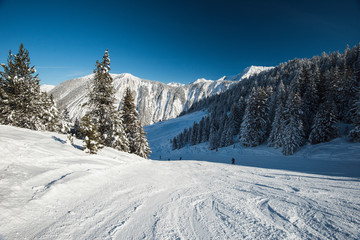 Fototapeta na wymiar Skiers on a piste in alpine ski resort