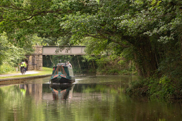 A boat slowly makes its way along a peaceful stretch of the Leeds & Liverpool Canal