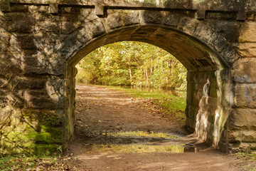 Fototapeta na wymiar Canal towpath stretches under the stone arch of bridge