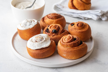 Delicious Cinnamon Rolls with cheese cream on a white plate. Copy space.