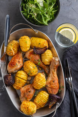 Barbecued chicken leg with boiled potatoes and vegetables on black background. Copy space. Top view.