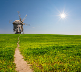 Fototapeta na wymiar historical wooden windmill among a green rural fields