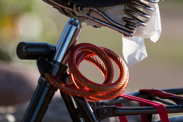 Old vintage simple bicycle with red padlock and plastic bag for raincover