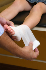 doctor making an ankle bandage to a girl, pediatric emergency.