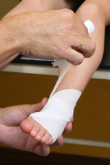 doctor making an ankle bandage to a girl, pediatric emergency.