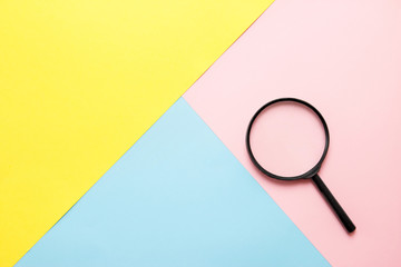 Magnifier on colored paper. Top view. Search concept