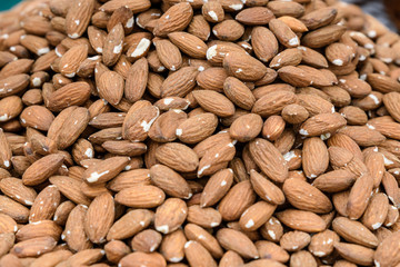 Close  up of a large group of salted fried almonds, brown food background