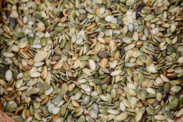 Close  up of a large group of salted pumpkin seeds, green and brown food background