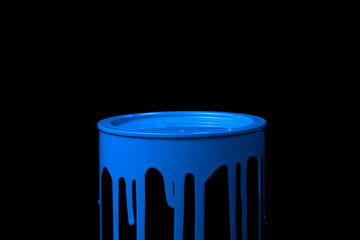 Blue paint flowing down on wall of metal bucket. Isolated over black background